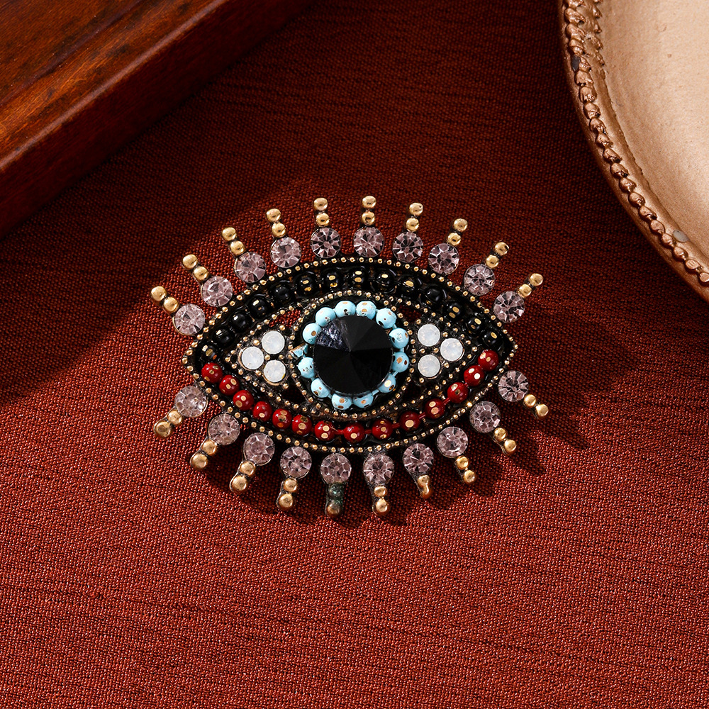 Broche vintage luxueuse et élégante haut de gamme, ornée de longs cils et d'un regard démoniaque, mettant en valeur une personnalité unique et exacerbée._voghion.com