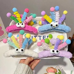 カラーツイスト棒の大きな目のぬいぐるみが女性の後頭部を挟んでサメのクリップを巻いています。