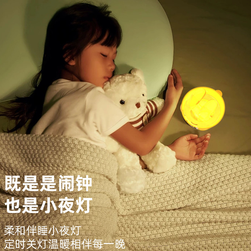 カラフルな雰囲気の恥ずかしがり屋のウサギは夜の明かりをたたいて目覚まし時計の寝室のベッドの上で乳をあげます。|undefined