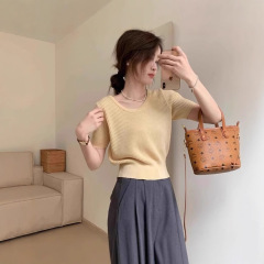 灰色の低い丸首のニットの半袖の女性の夏の薄い金の気質は腰を収めてやせている正肩のtシャツの半袖のゆったりしている上着を現します。
