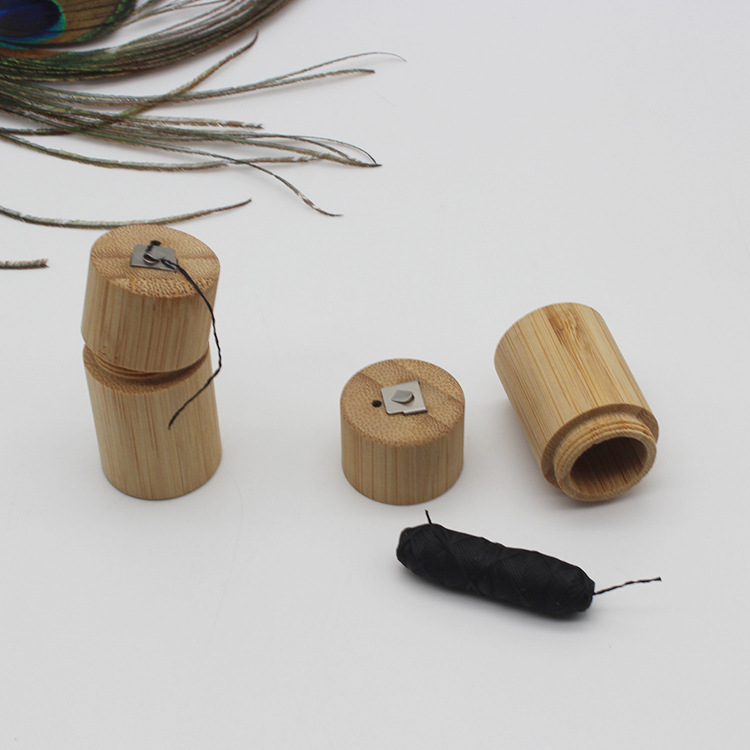 Light brown bamboo cylindrical container with metal clasp and black string designed as a portable biodegradable case for storing dental floss.