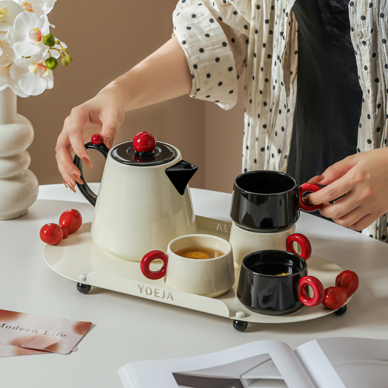 La ama de casa moderna es la misma creativa encantadora de alto valor de la cara con un conjunto de utensilios de agua de cerámica doméstica para invitados con un conjunto completo de tetera de té