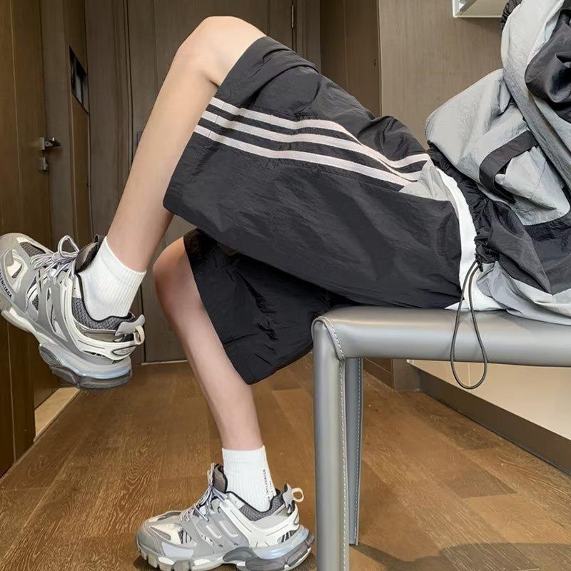 Pantalones cortos de secado rápido estadounidenses para hombres 2025 nuevos pantalones casuales de verano a rayas de cinco puntos tendencia deportiva suelta