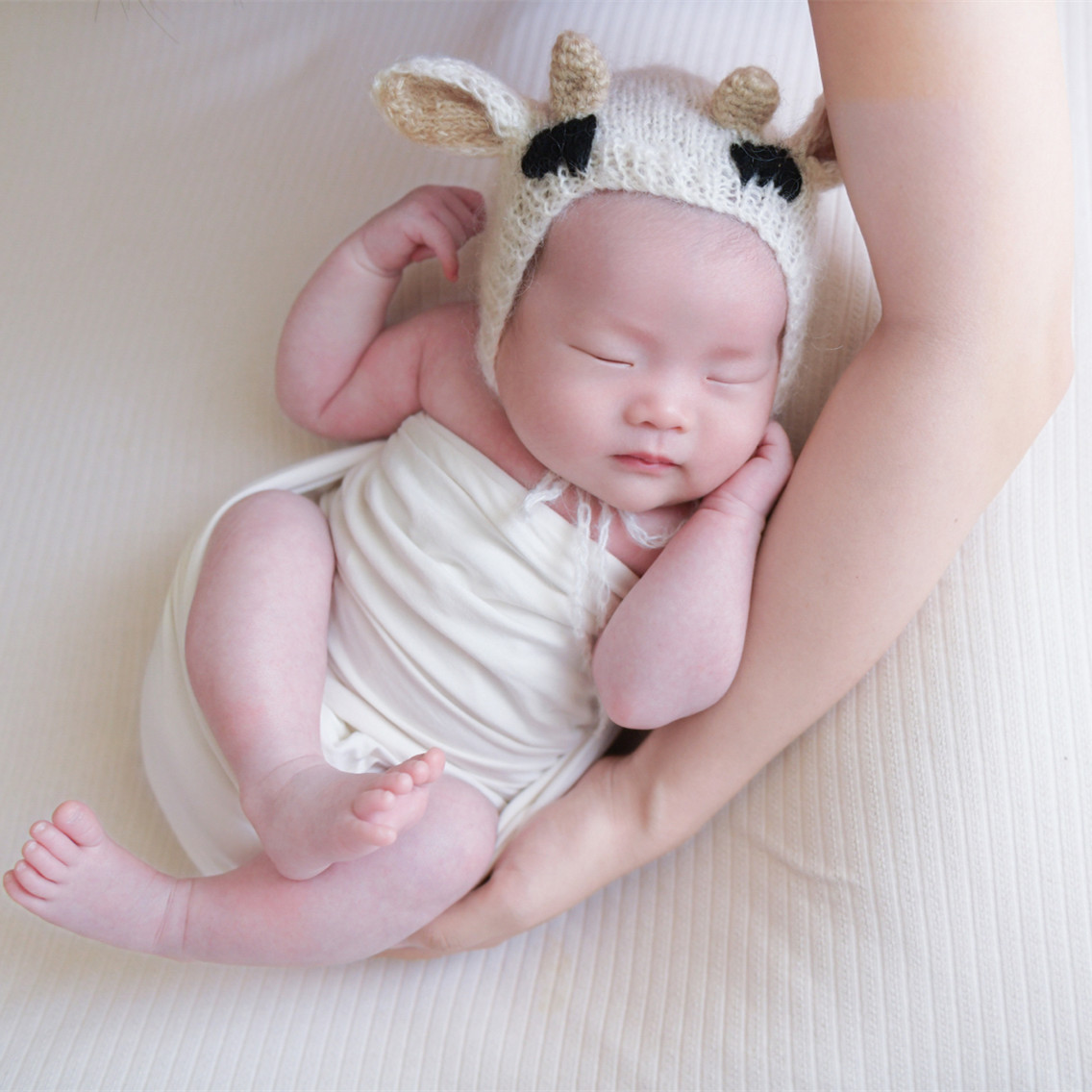 子供の写真を撮る服の影楼の赤ちゃんはいっぱいで毛糸の子牛の造形の帽子の人形を撮影します 日本産