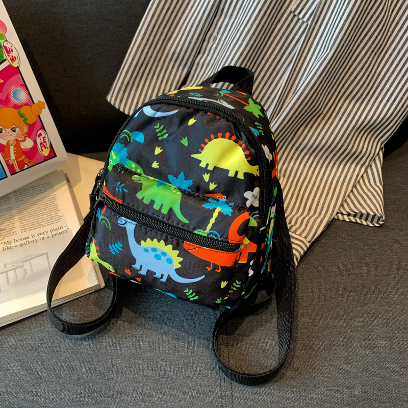 Mochila nueva al por mayor 2025, mochila de tela Oxford con diseño de dinosaurio de dibujos animados, mochila pequeña de gran capacidad para actividades al aire libre y ocio.