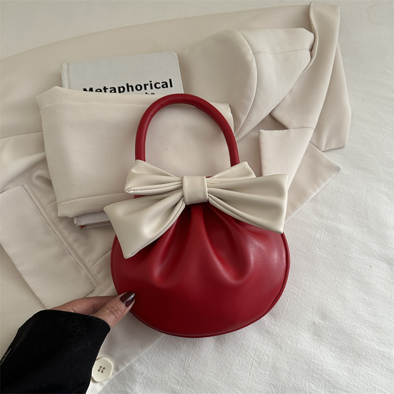 2025 primavera y verano nuevo nicho de diseño de arco bolsos portátiles de mujer alta sensación pequeña bolsa redonda roja