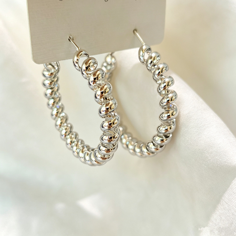 Trendy spiral-patterned earrings, exuding a luxurious and sophisticated aura, featuring a high-quality silver texture, a unique design, and an irregular shape, making them a standout piece of jewelry for women