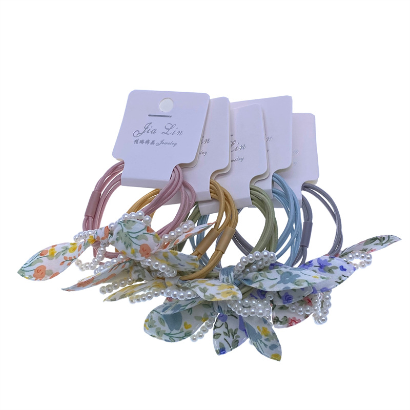 Etiqueta de estilo coreano accesorios para el cabello para niños Perla pequeña pajarita cuerda de pelo chica estudiante cabeza cuerda banda de goma dos yuanes suministro de la tienda