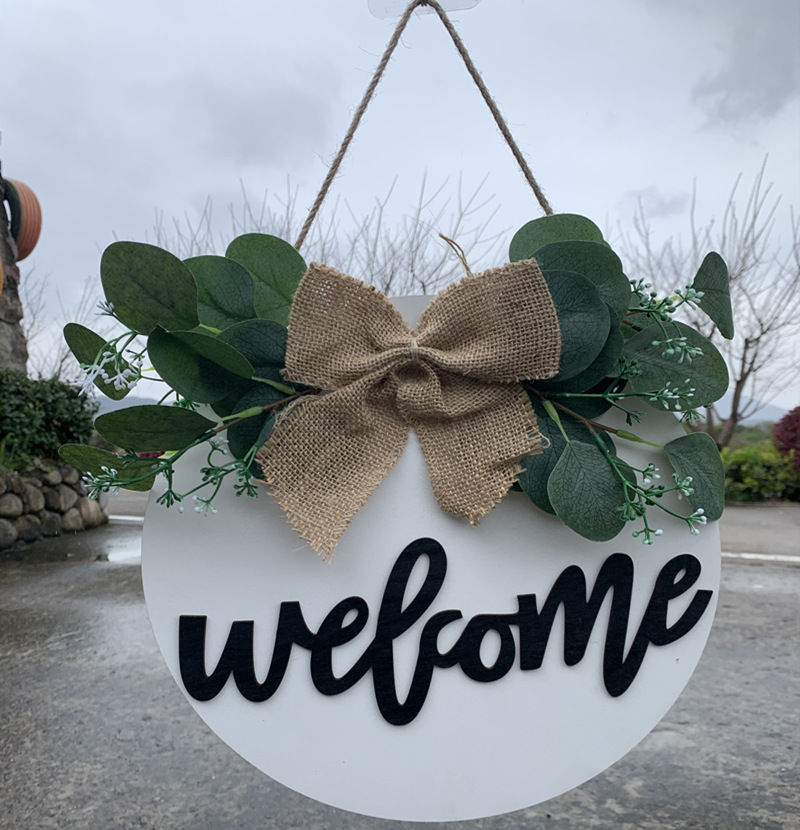 Olá estilo rural. A decoração circular inacabada da porta da frente recebe etiquetas e placas de madeira penduradas_voghion.com