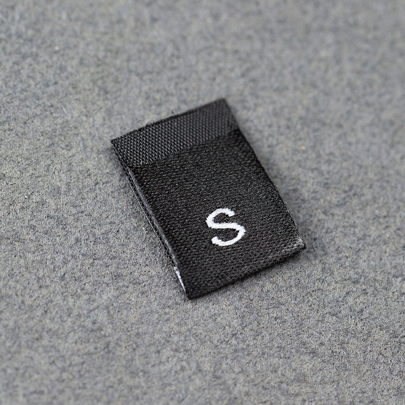 En stock Etiqueta de tamaño de alta densidad en blanco y negro Etiqueta de tamaño universal Etiqueta de código de letra inglesa Pantalones Etiqueta de código de cuello de camiseta