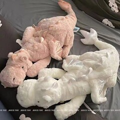 かわいい恐竜のぬいぐるみが腹ばいになっています。