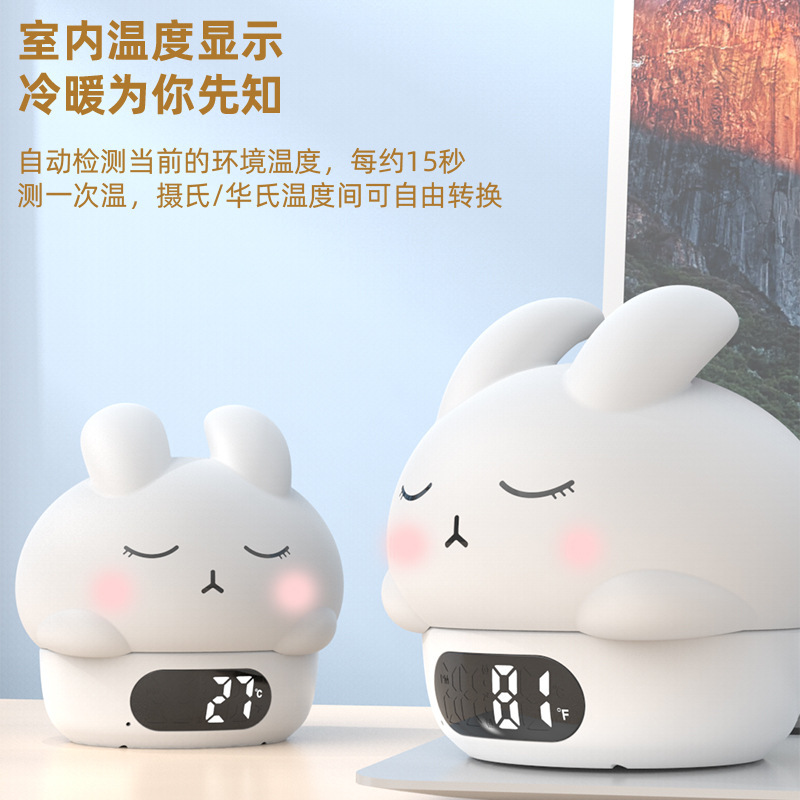 カラフルな雰囲気の恥ずかしがり屋のウサギは夜の明かりをたたいて目覚まし時計の寝室のベッドの上で乳をあげます。|undefined