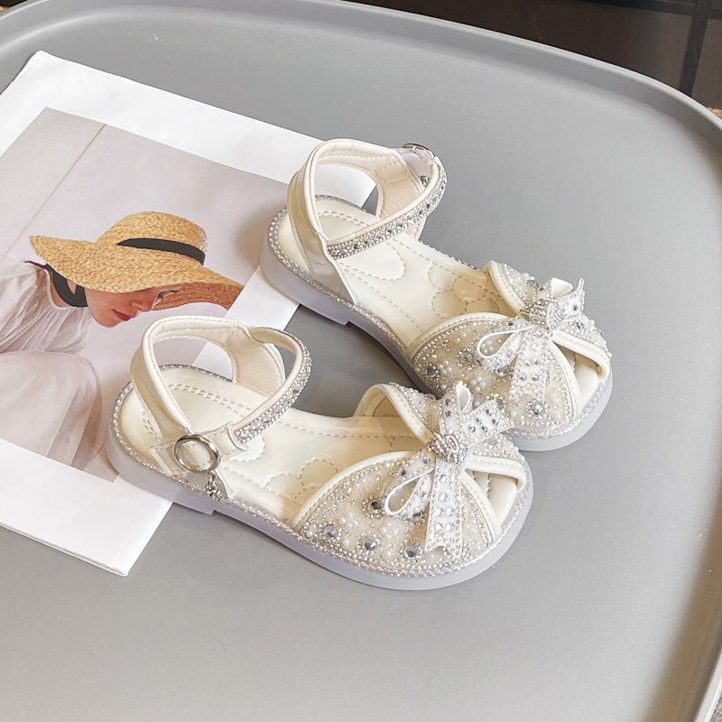 Sandalias Baotou para niñas 2025 verano nuevo estilo bowknot moda cristal princesa zapatos de playa para niños de suela suave marea