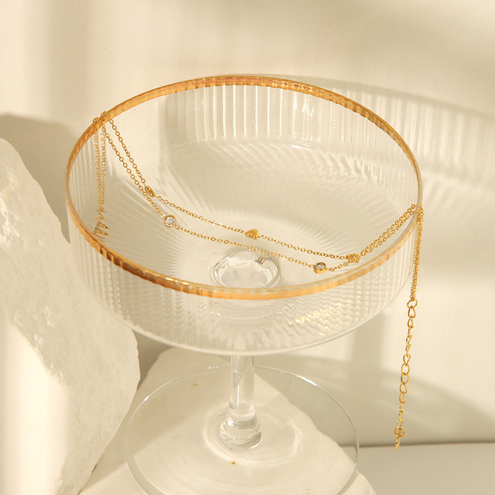 Estilo francés acero de titanio horno de 18K galvanoplastia de oro real doble amor circón tobillera verano femenino todo fósforo joyería de playa