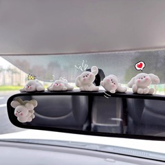 車の中でブツブツと赤い顔をしています。白い犬がアニメを飾っています。