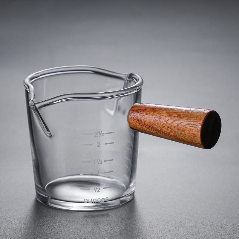 側木は口の小さいミルクの杯の透明なガラスを目盛りの測定の杯のエスプレッソのオンスの杯の小さいミルクの缶を持ちます。|undefined