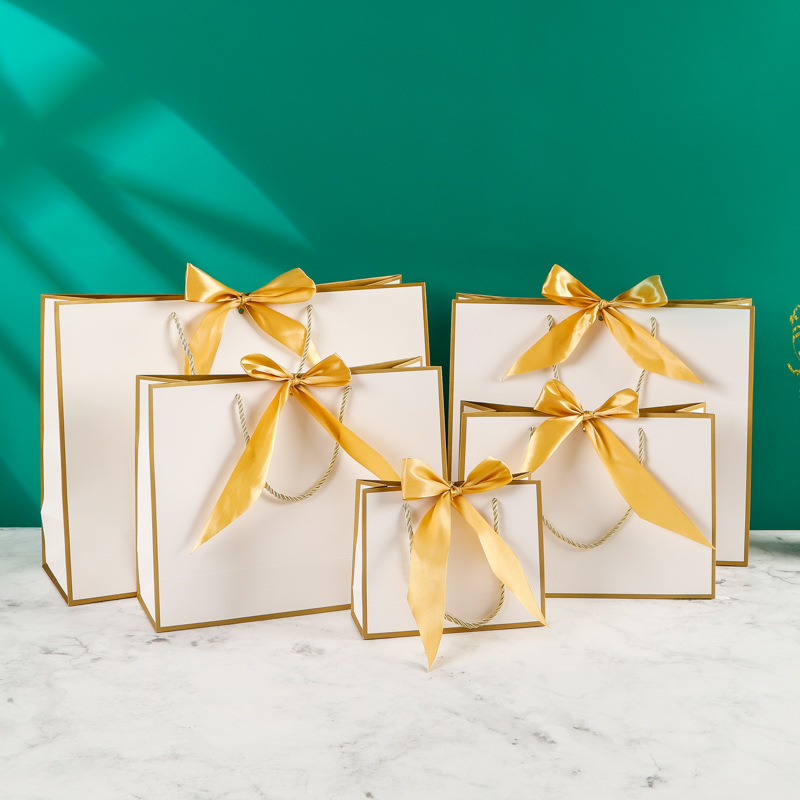 Fábrica al por mayor arco bolsa de papel portátil ropa bolsa de embalaje bolso de cartón blanco con logotipo impreso