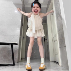 フランスの杏色の袖なしの首のサスペンダーのワンピースの子供の夏の2025新型の休暇の小さい子供は腰の短いスカートを収めます。