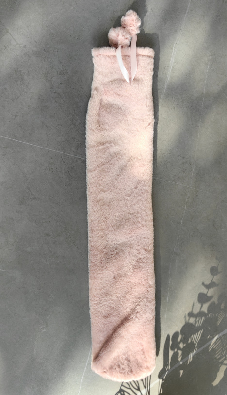 긴 핑크 수국 천 커버에 뜨거운 물병이 들어있습니다.