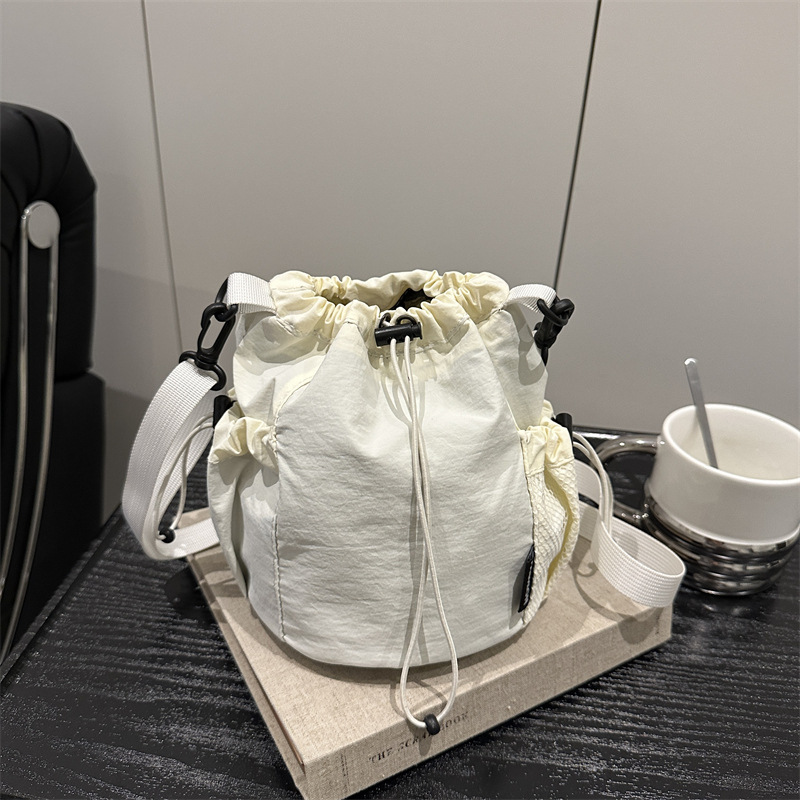 2025 verano nuevo nicho japonés y coreano tirar de la correa de tela de un hombro mochila de mujer ligera perezosa bolsa de cubo de feng shui