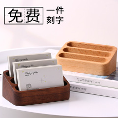 木製のクリエイティブな名刺入れのデスクトップの前に木製の名刺棚があります。