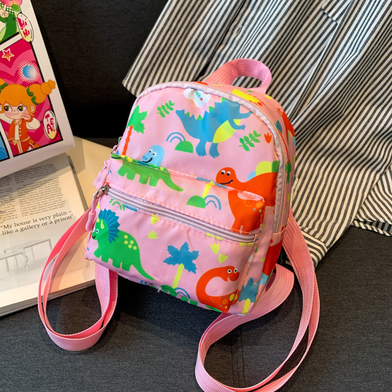 Mochila nueva al por mayor 2025, mochila de tela Oxford con diseño de dinosaurio de dibujos animados, mochila pequeña de gran capacidad para actividades al aire libre y ocio.