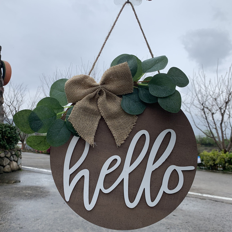 Olá estilo rural. A decoração circular inacabada da porta da frente recebe etiquetas e placas de madeira penduradas_voghion.com