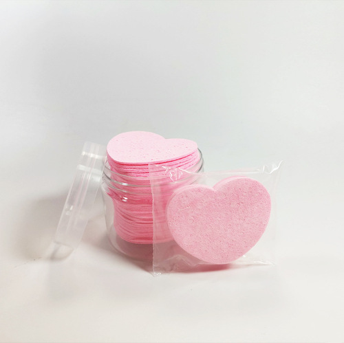 Compressed heart-shaped wood pulp cotton facial puff for washing face, cleansing, makeup removal, and powder application; can be soaked in water to transform into a large sponge facial puff.