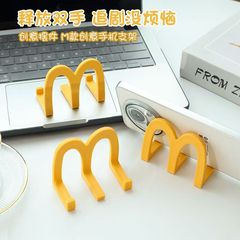 マドンダのデスクトップの携帯電話のスタンドの小さい置物のアイデアの事務室は携帯電話の棚の学生を置いて劇の神器を追いかけることを使います。