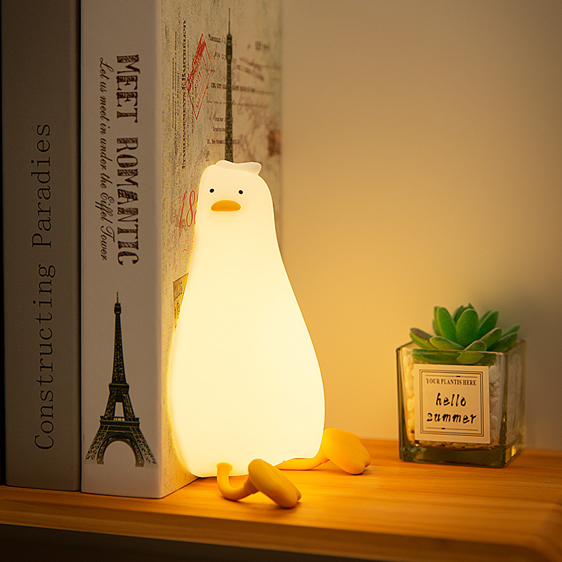 横になっているアヒルの小夜灯が明かりをたたいてシリコンledが寝返りを打ったアヒルの充電ベッドの頭に寝ている携帯電話スタンドの夜灯のアイデア