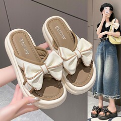 韓国版の大きい蝶結びの柔らかい底の快適なスリッパの厚い底の百合の1字の女性は2025夏の新型のビーチシューズを着ます。