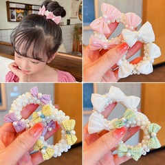 子供の団子の髪のひもの小さい女の子の真珠の蝶結びの甘い髪の輪の女の子は髪の弾力性の良い輪ゴムを傷つけません。