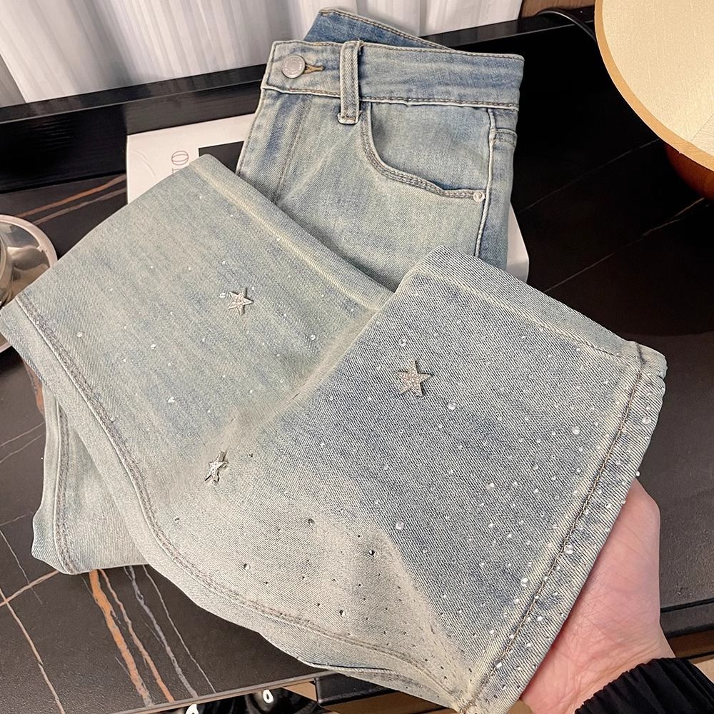 Calça jeans feminina de cintura alta com detalhes em estrelas e strass, modelagem flare, visual que afina a silhueta e favorece mulheres de estatura baixa. Jeans feminino da moda para a primavera._voghion.com