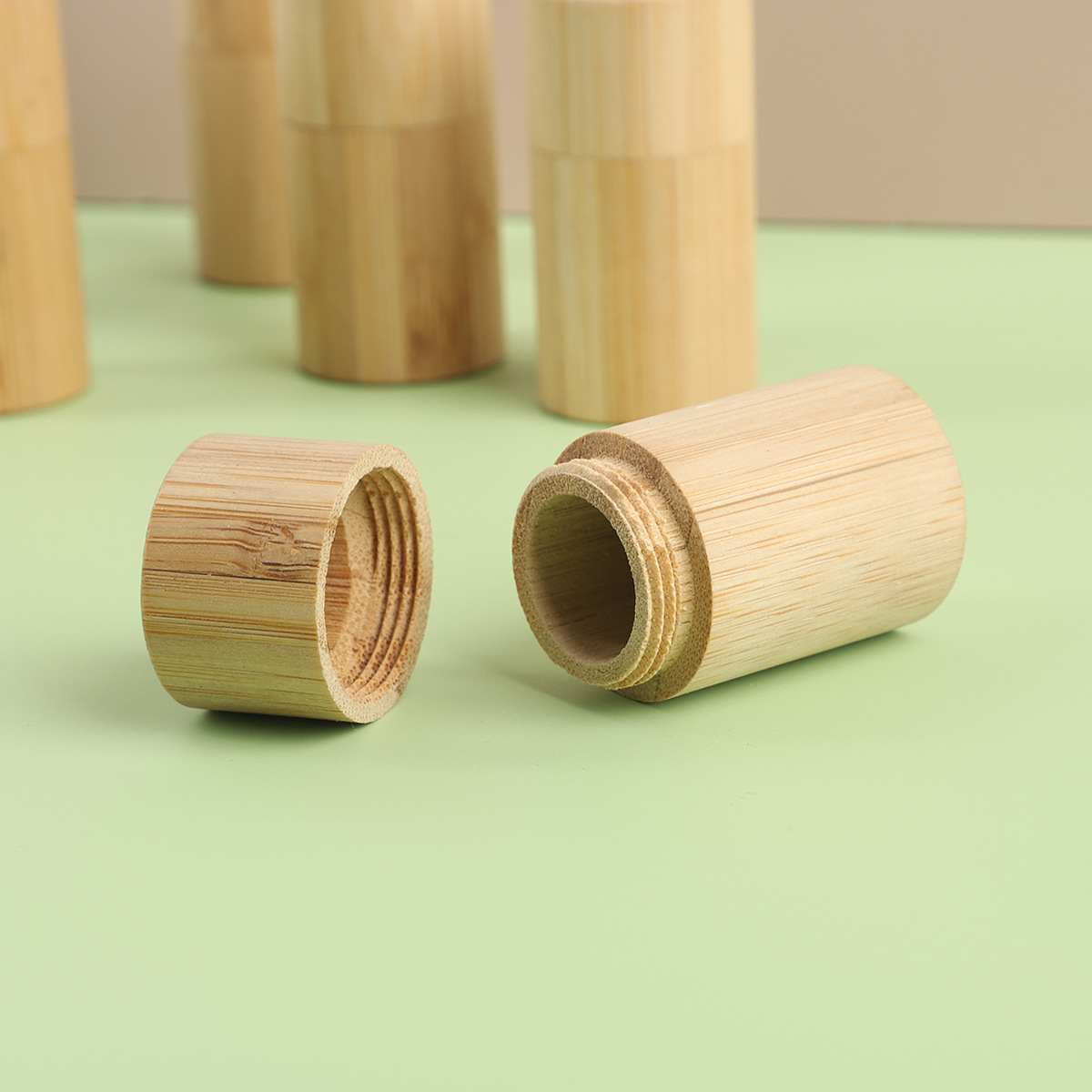Natural bamboo cylindrical floss tube with matching lid featuring visible wood grain and threaded interior for secure closure in a biodegradable portable case.