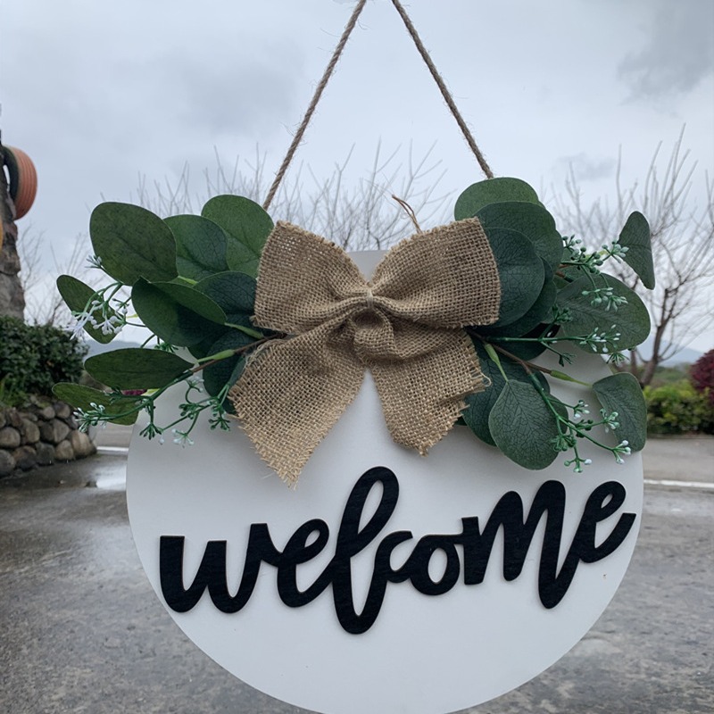Olá estilo rural. A decoração circular inacabada da porta da frente recebe etiquetas e placas de madeira penduradas_voghion.com