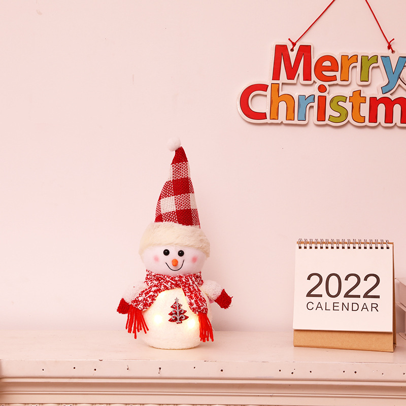 クリスマス発光雪だるま人形のデスクトップに子供の祝日のプレゼントを飾っています。|undefined