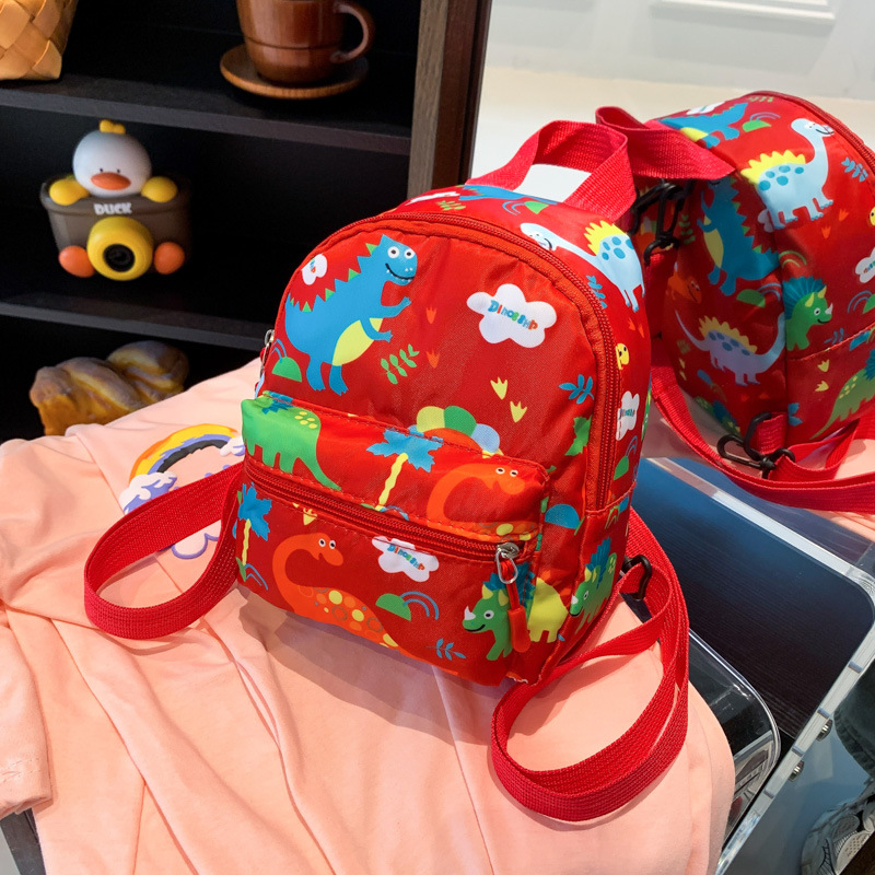 Mochila nueva al por mayor 2025, mochila de tela Oxford con diseño de dinosaurio de dibujos animados, mochila pequeña de gran capacidad para actividades al aire libre y ocio.