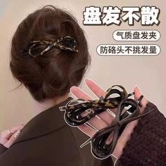 革の蝶結びのツイストヘアクリップの女性の後頭部の半分は髪を刺します。