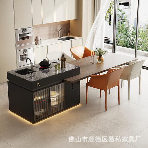 A stone slab island table with integrated tea table, induction cooktop, and extendable design, creating a versatile floating island in an open-concept kitchen.