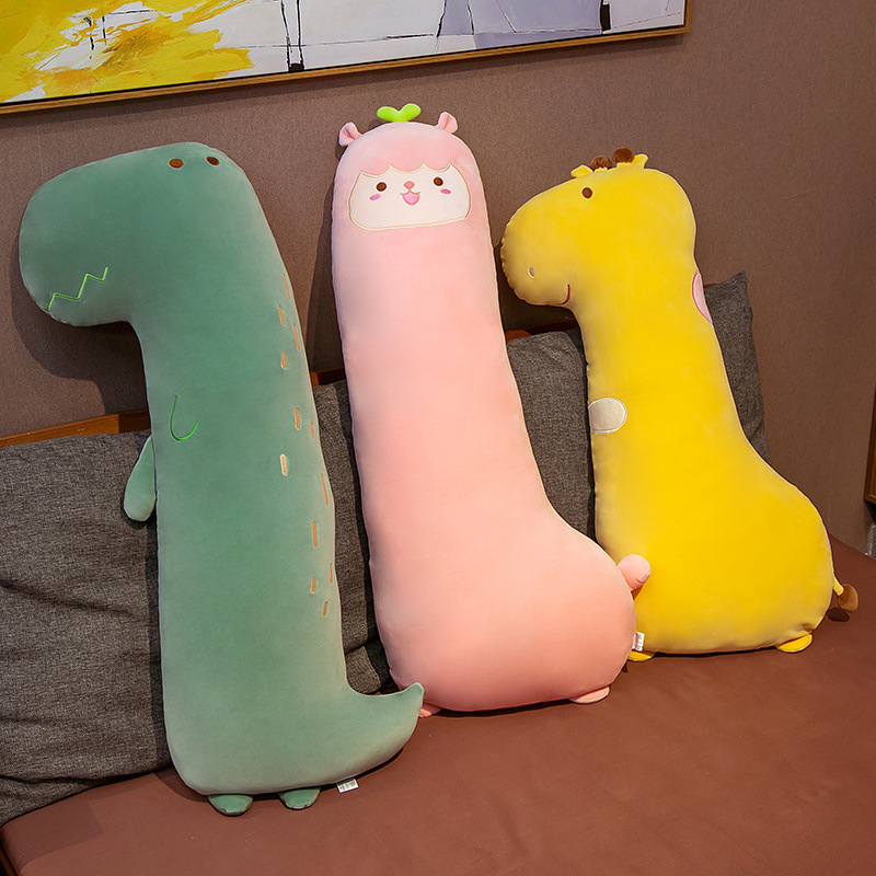 かわいい恐竜の長い抱き枕のぬいぐるみのベッドの上で女の子が寝ています。|undefined