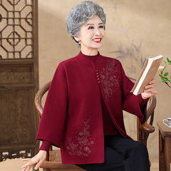 お年寄りの秋の服の女性のおばあさんはコートを着ます。