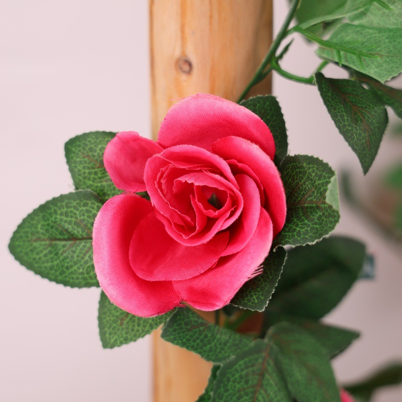 Simulación de flores falsas rosas de caña colgando la pared tubería de drenaje envuelta hoja verde que cubre la parte superior de la decoración de boda de plástico