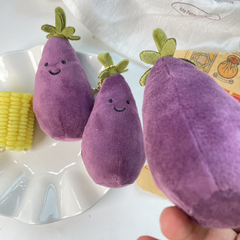 かわいい超萌えナスのほほえみ野菜の表情はぬいぐるみの息子の包みのペンダントのゲーム城を包んで子供のプレゼントをつかみます。|undefined
