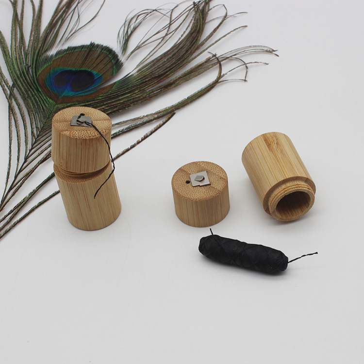 Light brown bamboo cylindrical portable biodegradable case with silver metal clasp black string matching lid and inserted black tampon.