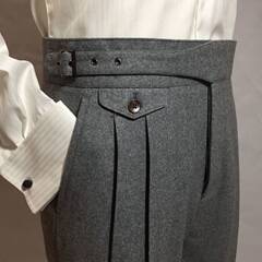 ウールのズボンの男性はまっすぐな筒を巻いてゆったりしています。