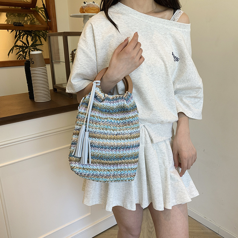 Versión coreana del bolso de cubo de nicho 2025 verano nuevo bolso femenino a rayas bolso de color en contraste bolso tejido con borlas de paja marea