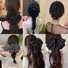 黒のレトロな波点のスカートは蝶結びを並べてフランスの半分の髪の低い馬尾のサメのクリップを挟みます。