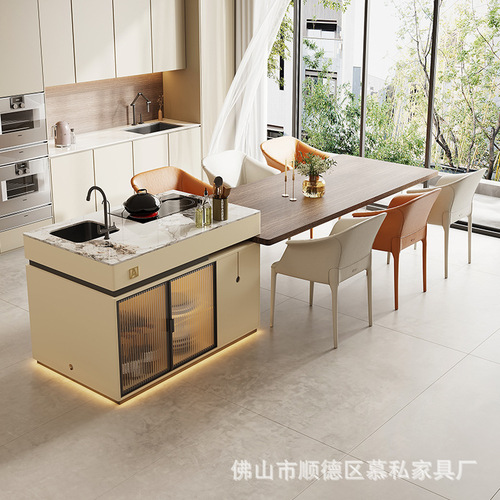 A stone slab island table with integrated tea table, induction cooktop, and extendable design, creating a versatile floating island in an open-concept kitchen.