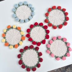 完成した手作りのバラの花束コースター、毛糸のかぎ針編みカップ、手持ちの花束、クリエイティブなギフト、編まれた花のコースター