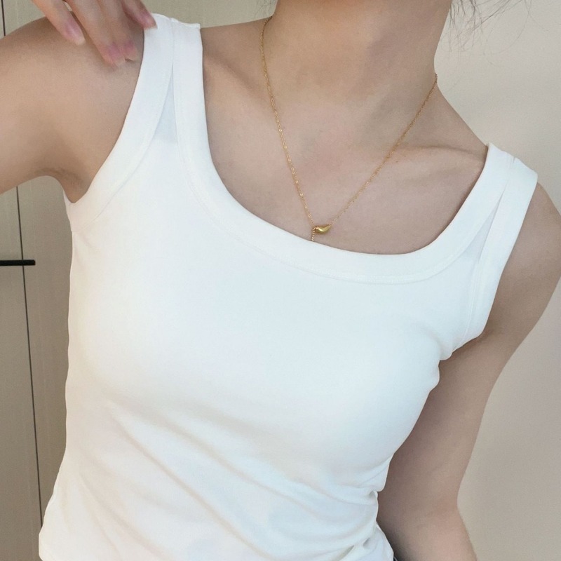 純色のベストのストラップの女性は胸のクッションを持っています。|undefined